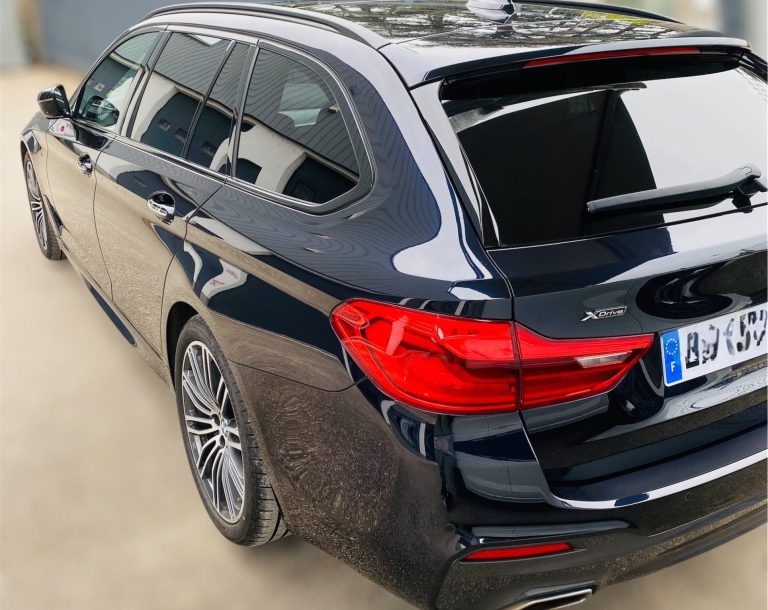 Voiture noire station wagon de profil, avec des lignes élégantes et des jantes en alliage.